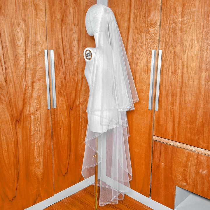 Sheer bridal tulle fabric of a waltz length two tier wedding veil with a pencil edge and blusher on a mannequin.