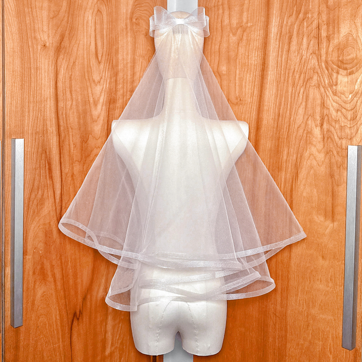 Elbow length two tier horsehair wedding veil with bow accent shown from the back on a bridal mannequin.