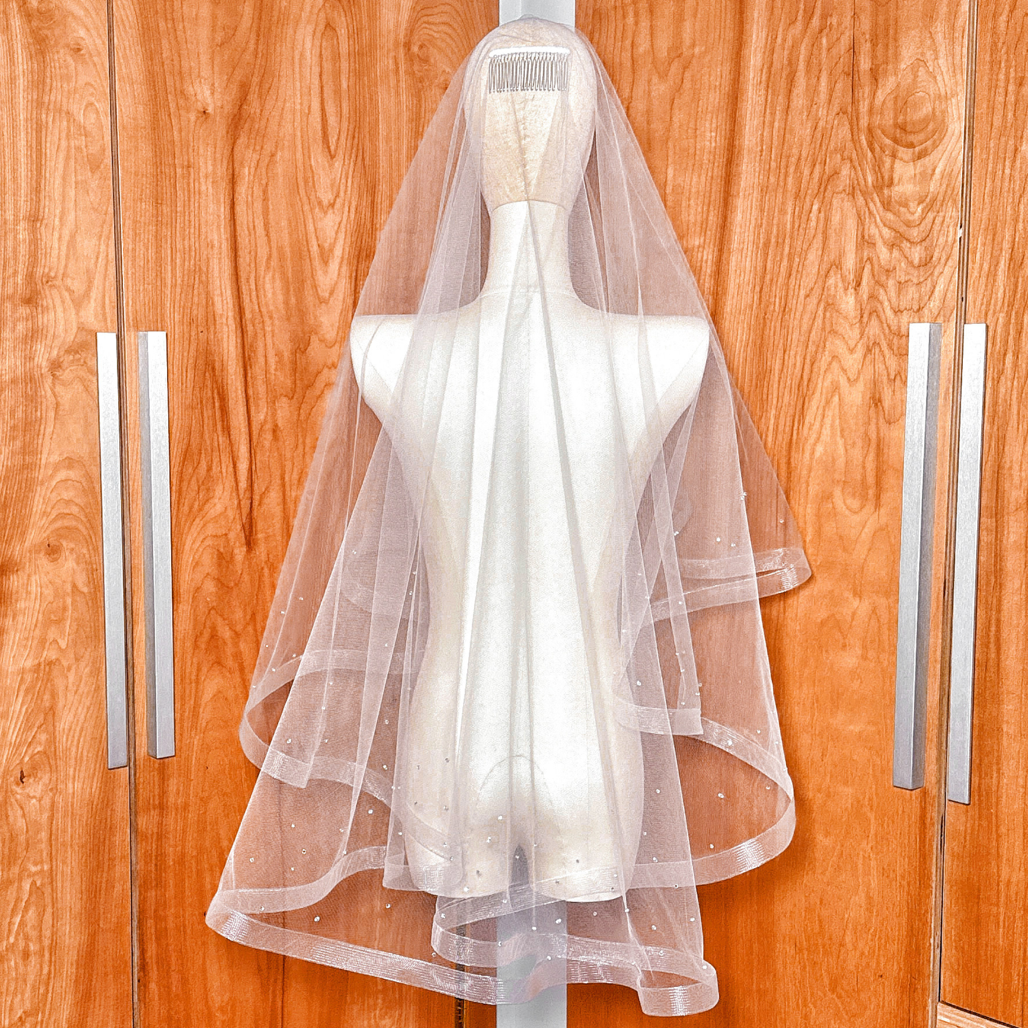 A fingertip length two tier horsehair wedding veil with scattered rhinestones featuring a structured horsehair trim.