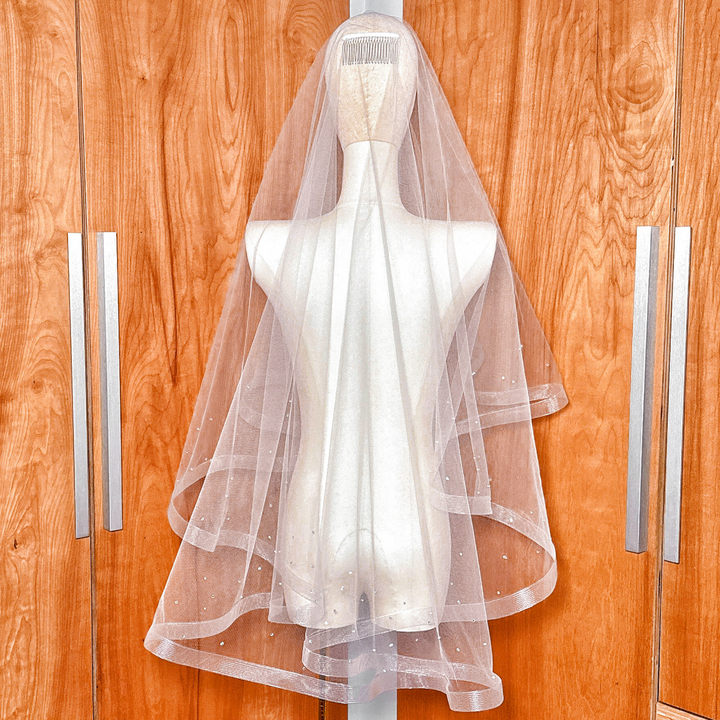 A fingertip length two tier horsehair wedding veil with scattered rhinestones featuring a structured horsehair trim.