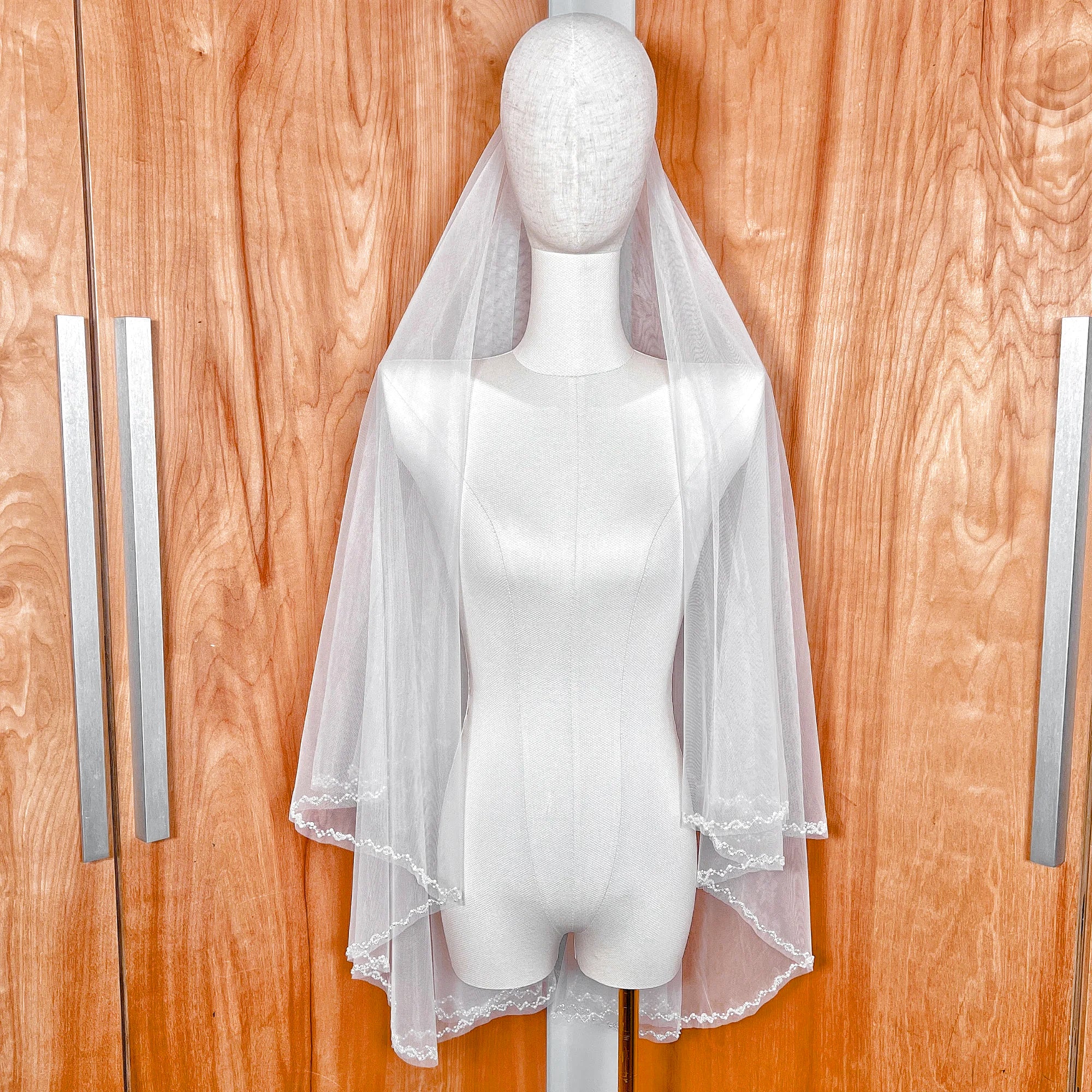 Detailed view of the layering on a fingertip-length two-tier wedding veil with beaded edge.