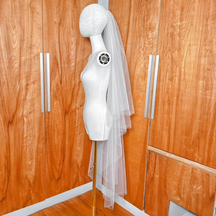 Side view of a waltz length two tier veil with a shimmering gold metallic edge and blusher on a mannequin.