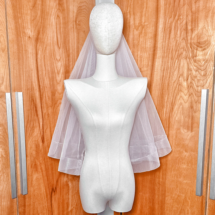 A classic elbow length two tier wedding veil with a 2 1/2" horsehair border and blusher attachment.