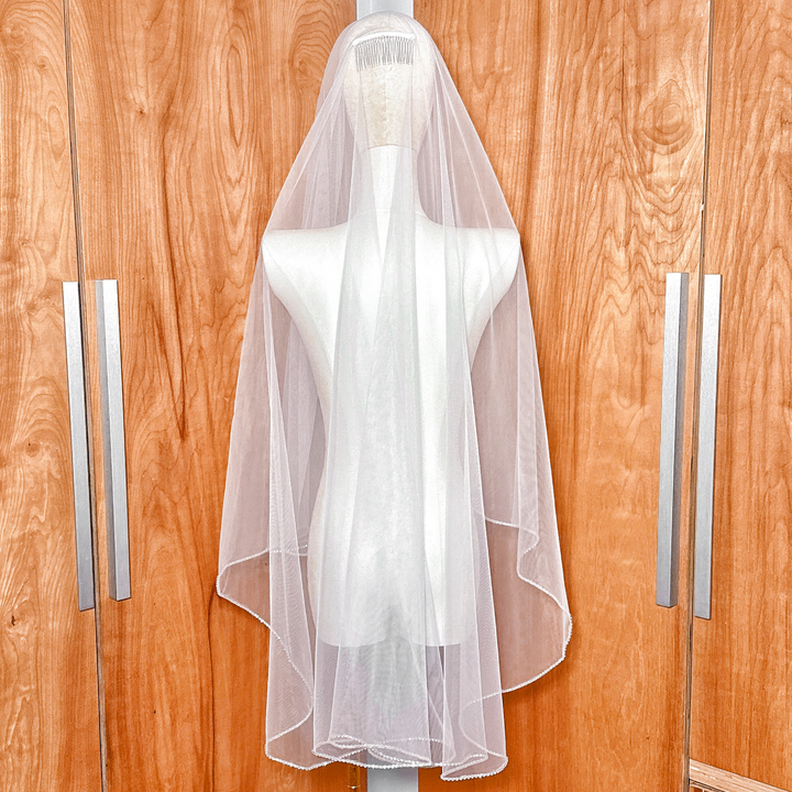 Rear view of a fingertip length two tier wedding veil with shimmering rhinestone edge trim.