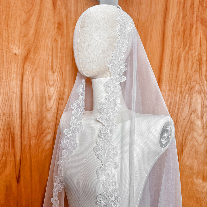 Top view showing the butterfly motif lace framing the face and head on a bridal mannequin.