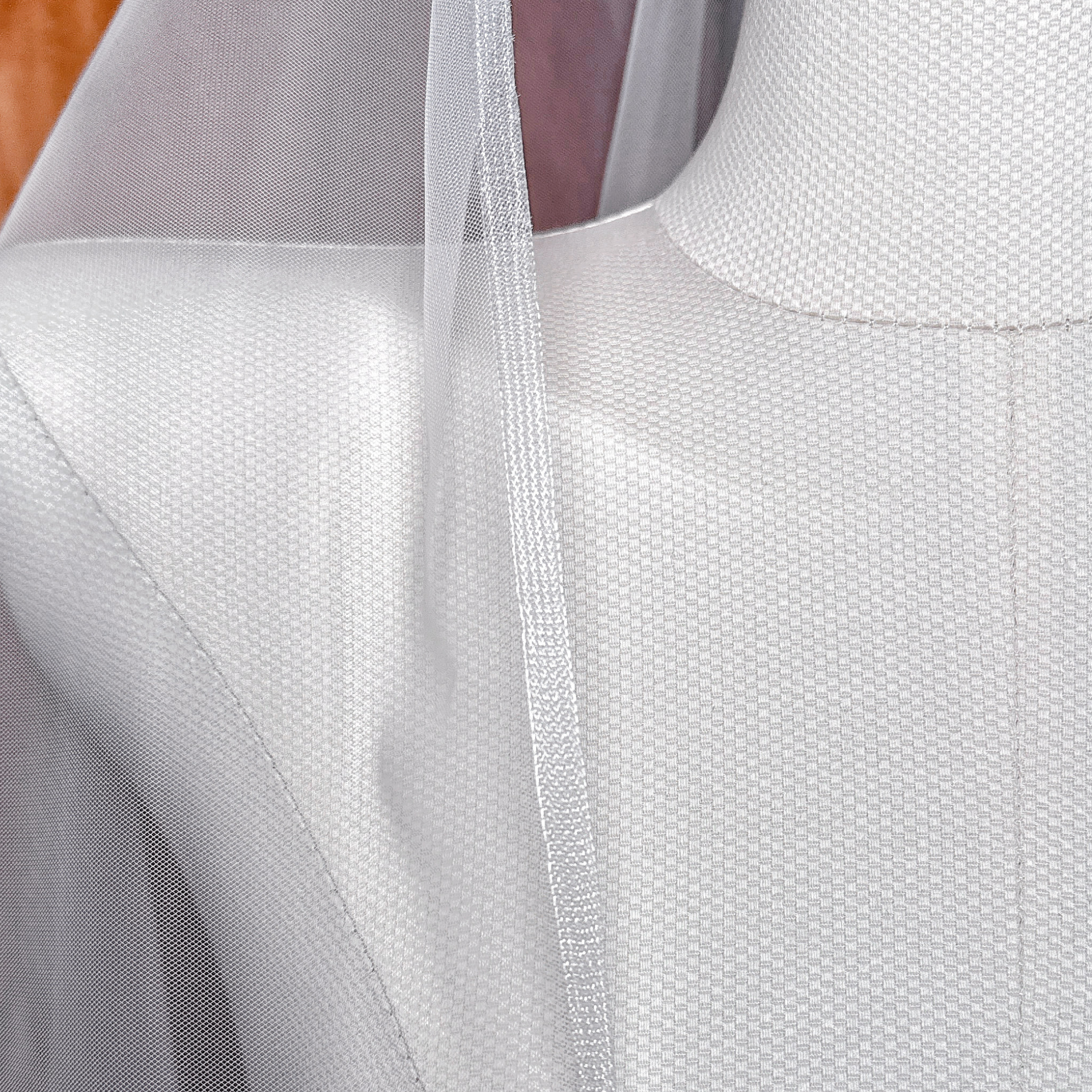 Close view of a ivory cascade fingertip length wedding veil with horsehair trim draped over a bridal mannequin.
