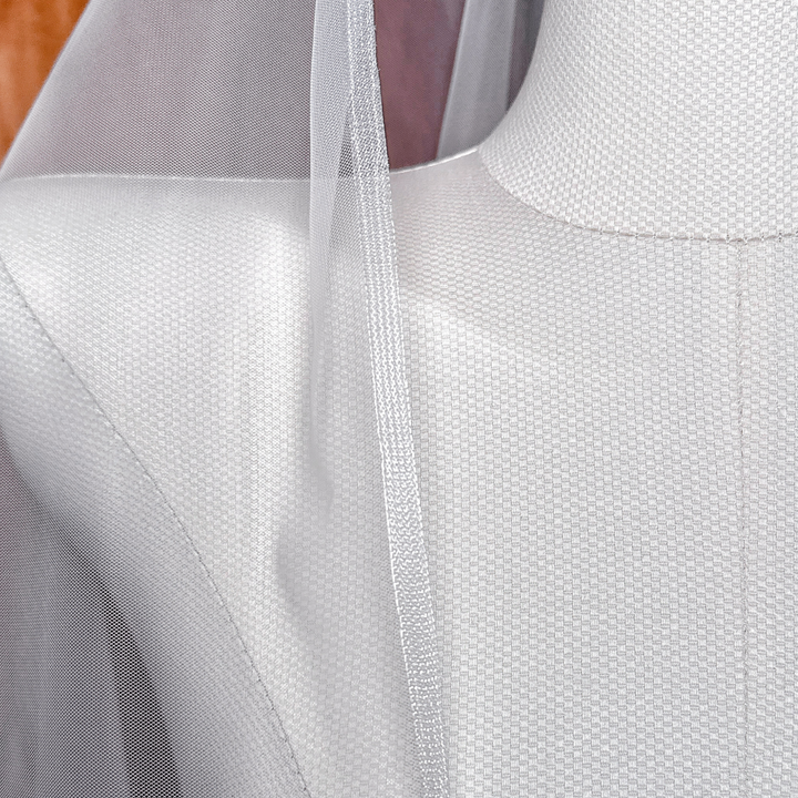 Close view of a ivory cascade fingertip length wedding veil with horsehair trim draped over a bridal mannequin.