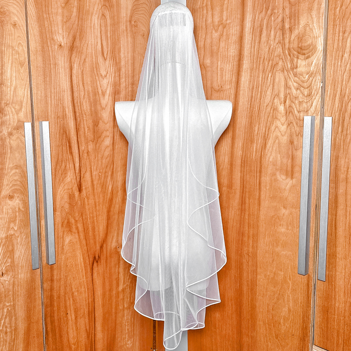 Top view of the secure comb attachment on the cascade fingertip wedding veil with corded edge.