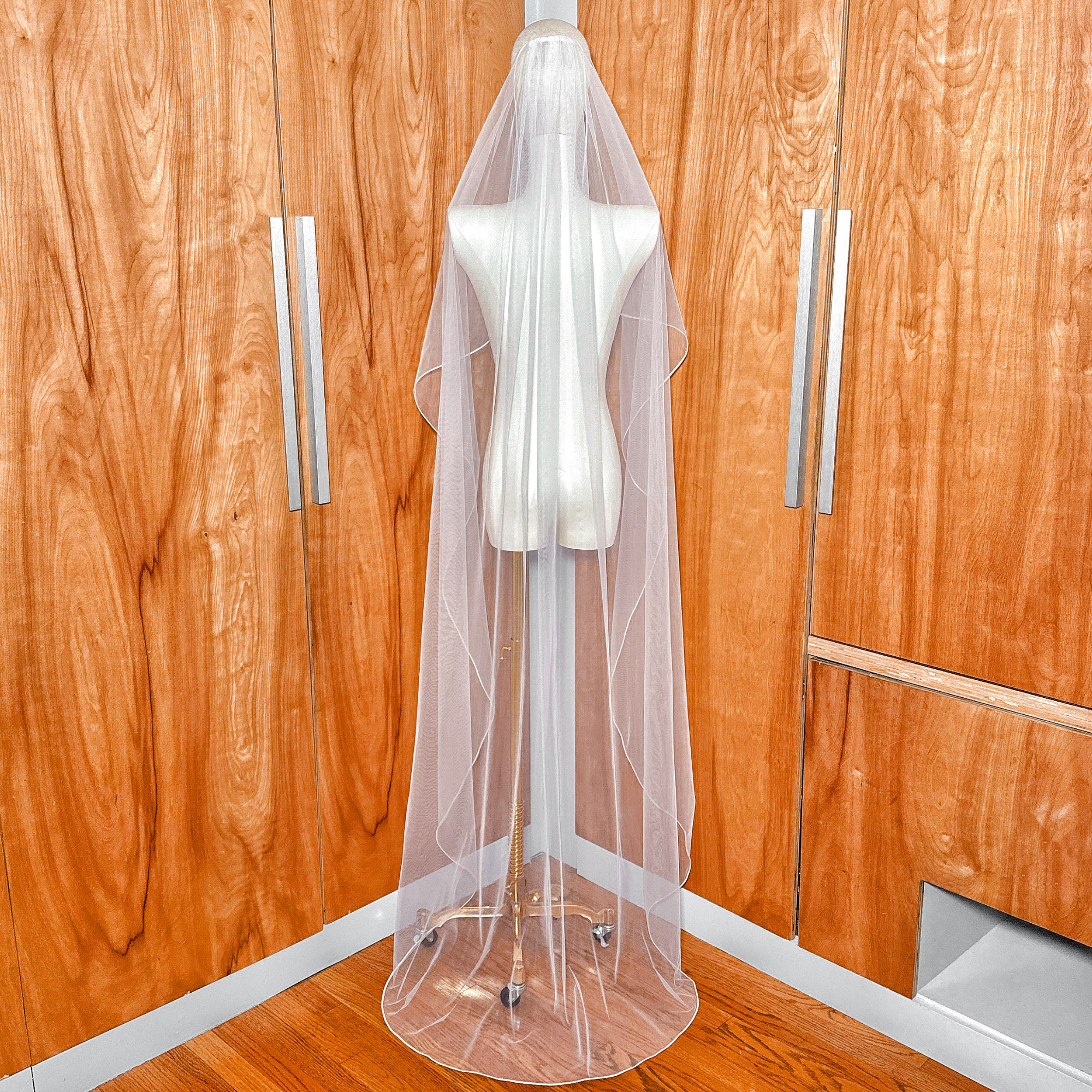 Full-length back view showing the floor-length cascade wedding veil with detailed corded edging.