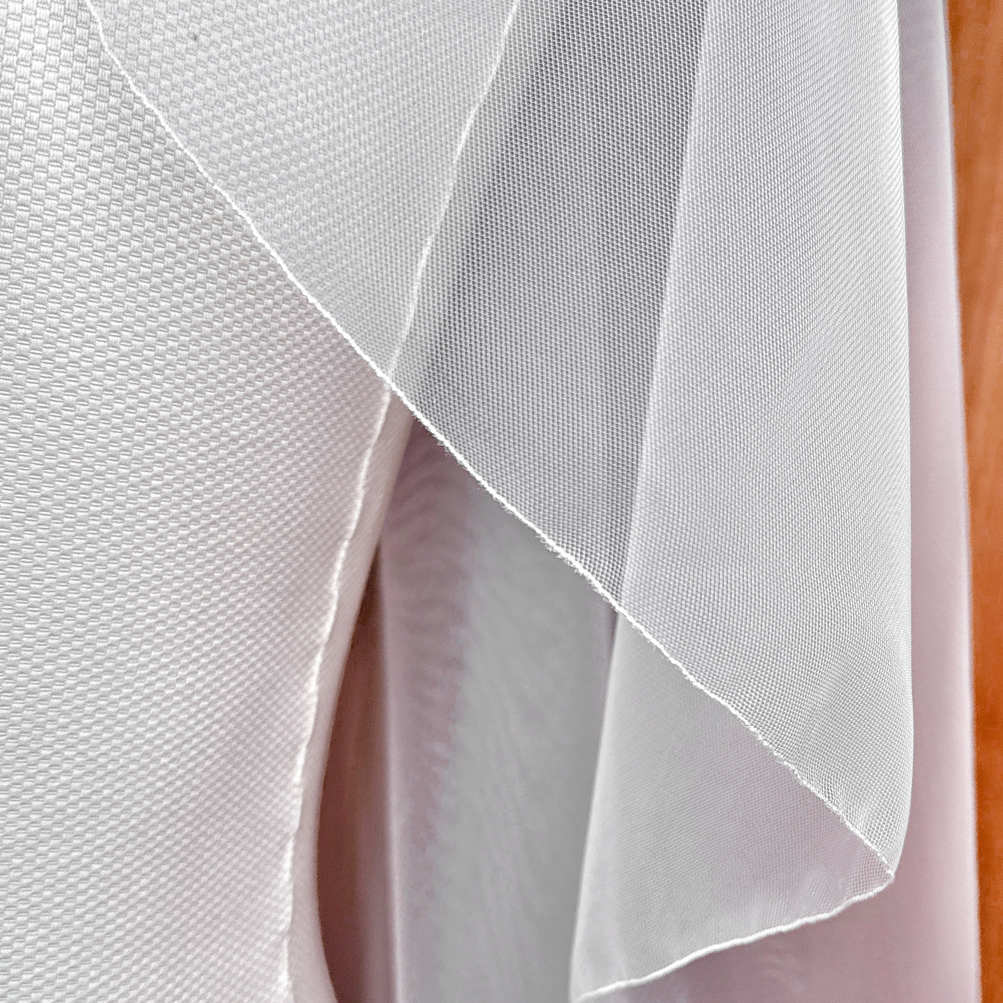 Detailed close-up showing the distinct individual tiers of a sheer cascade hip length wedding veil with a fine pencil edge.