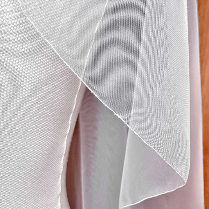 Detailed close-up showing the distinct individual tiers of a sheer cascade hip length wedding veil with a fine pencil edge.