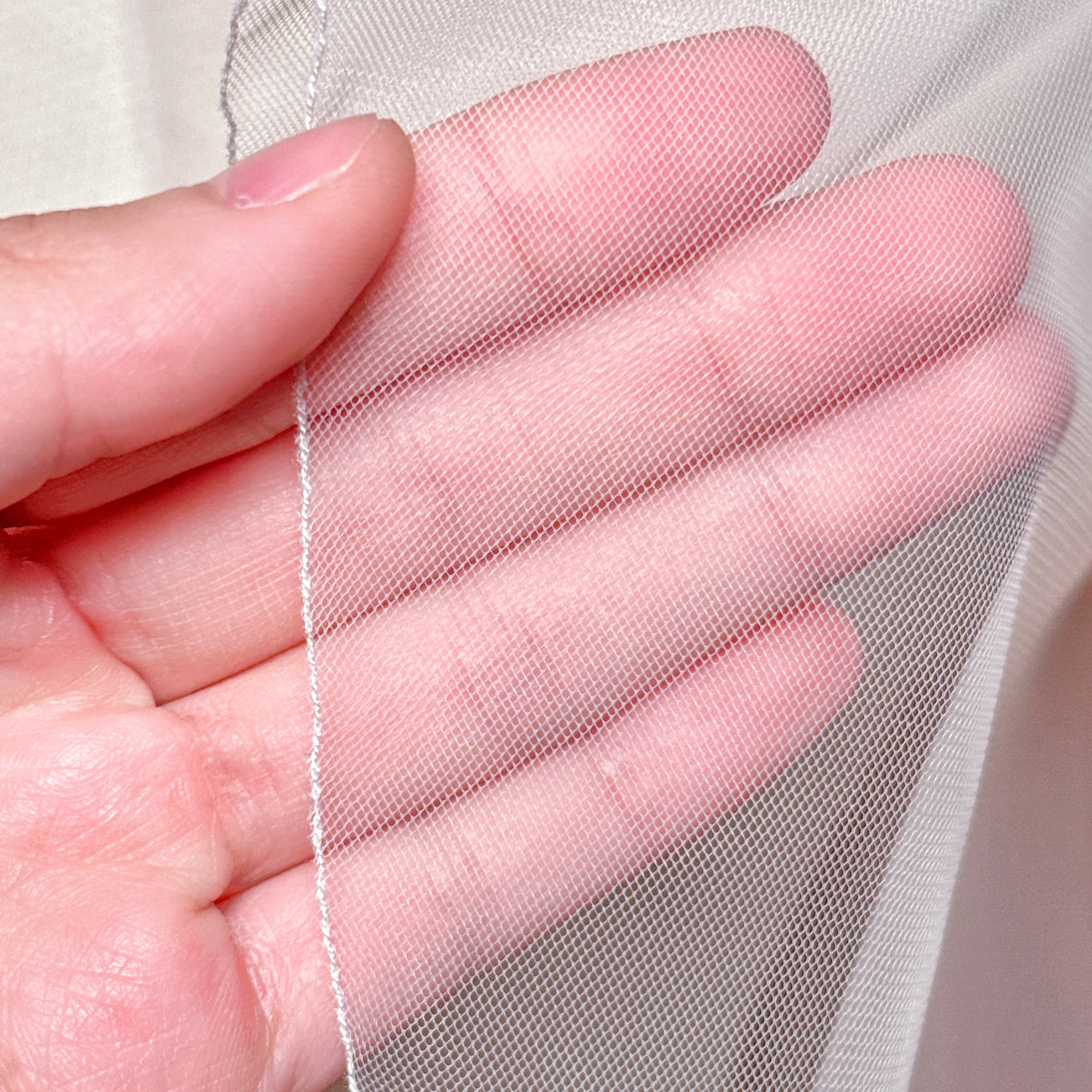 Close-up of the precise pencil edge stitching on a sheer cascade hip length wedding veil.