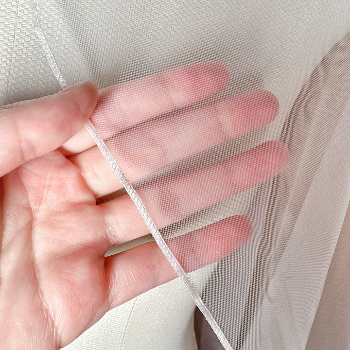 Close-up shot of the delicate micro ribbon trim on a cascade knee length wedding veil.