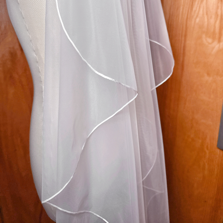 Close-up shot of the delicate micro ribbon trim on a cascade waltz length wedding veil.