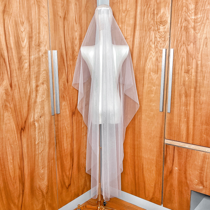 Rear view showing the graceful waterfall drape of the waltz length cascade wedding veil.