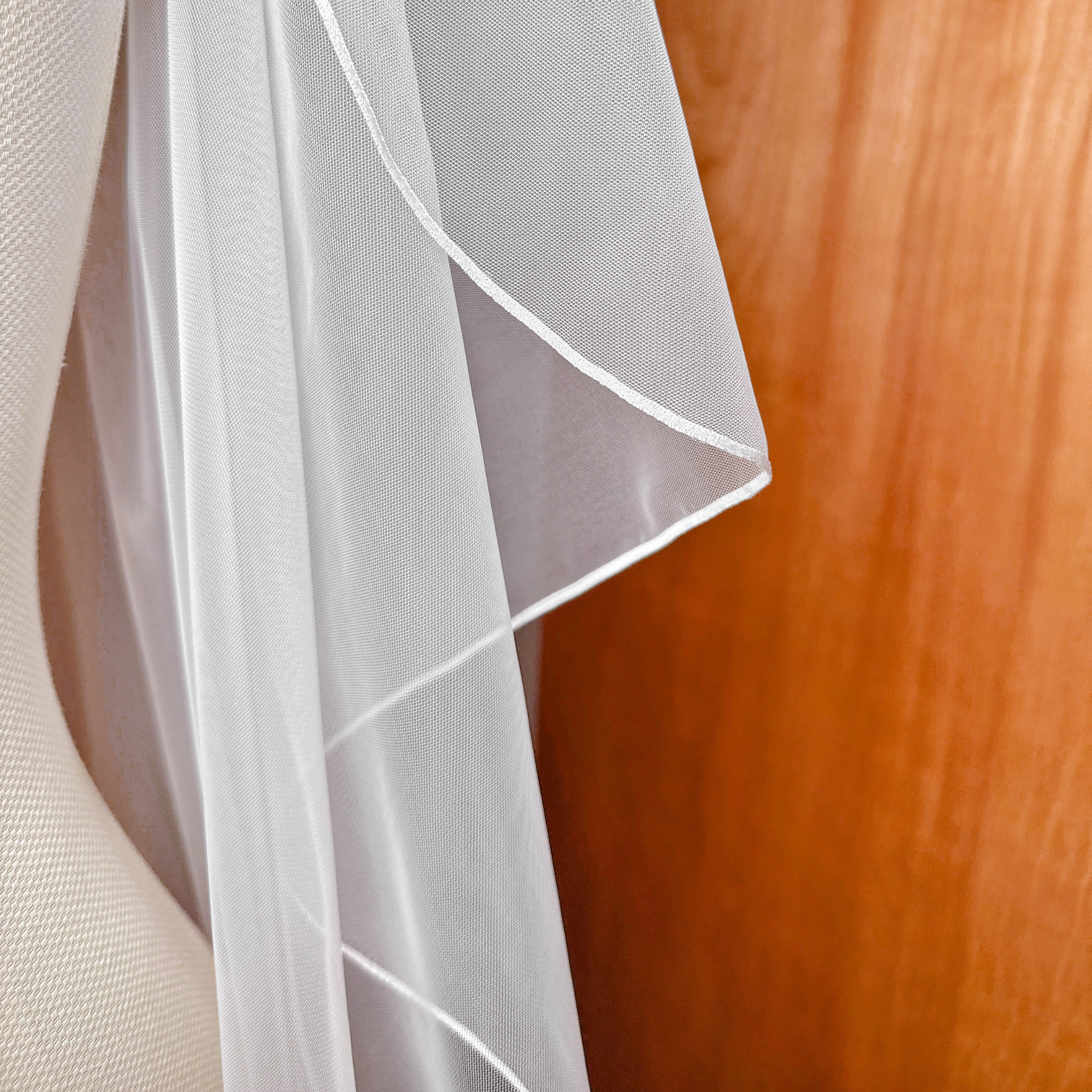 Close-up of the sheer white tulle fabric on a cascade waltz length wedding veil.
