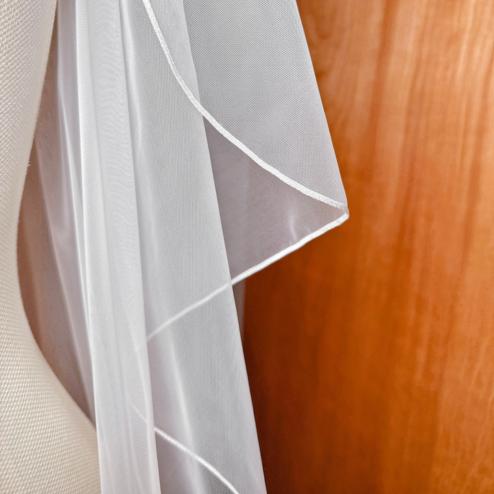 Close-up of the sheer white tulle fabric on a cascade waltz length wedding veil.