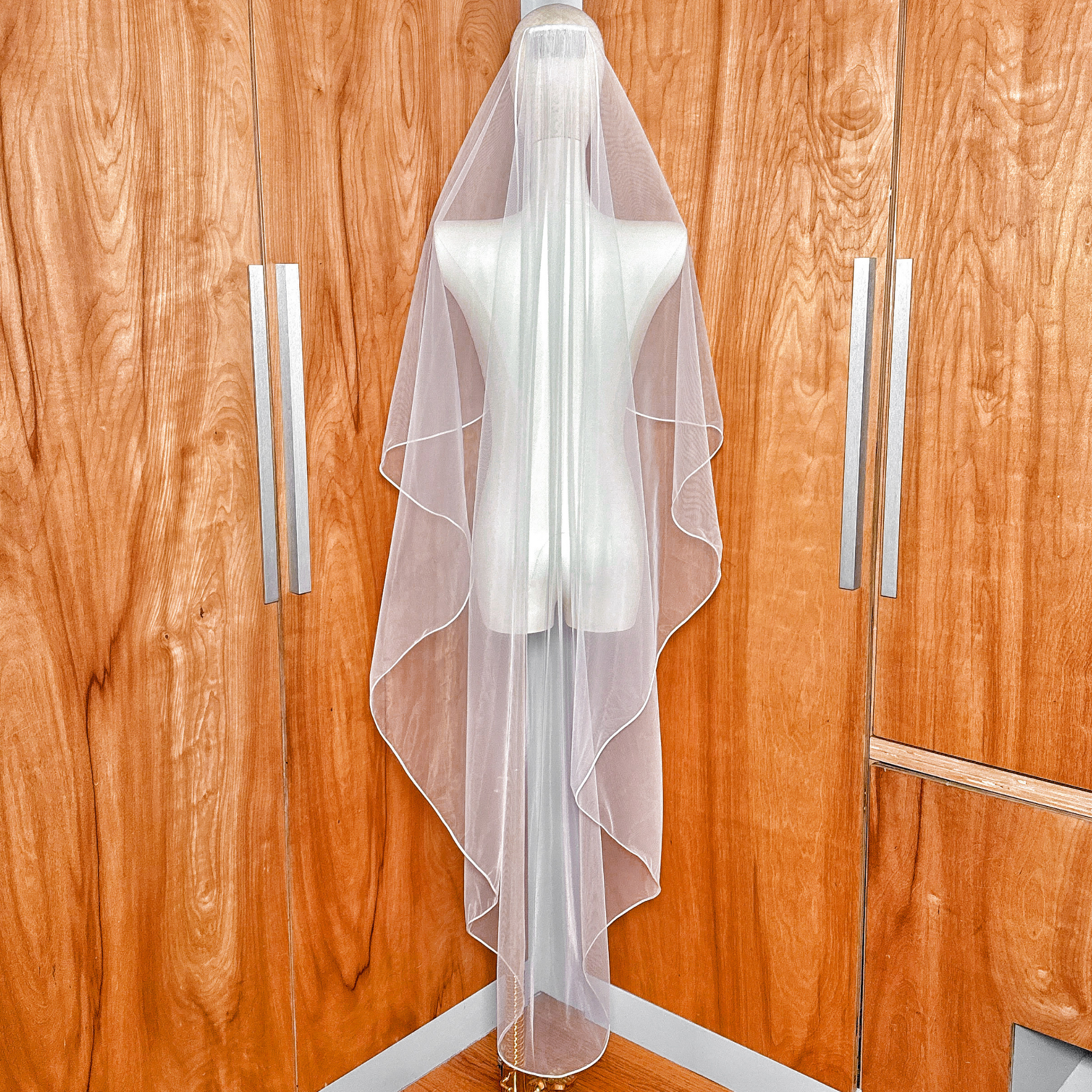 Full-length display showcasing the elegant drape of the Cascade Waltz Wedding Veil with Corded Edge.