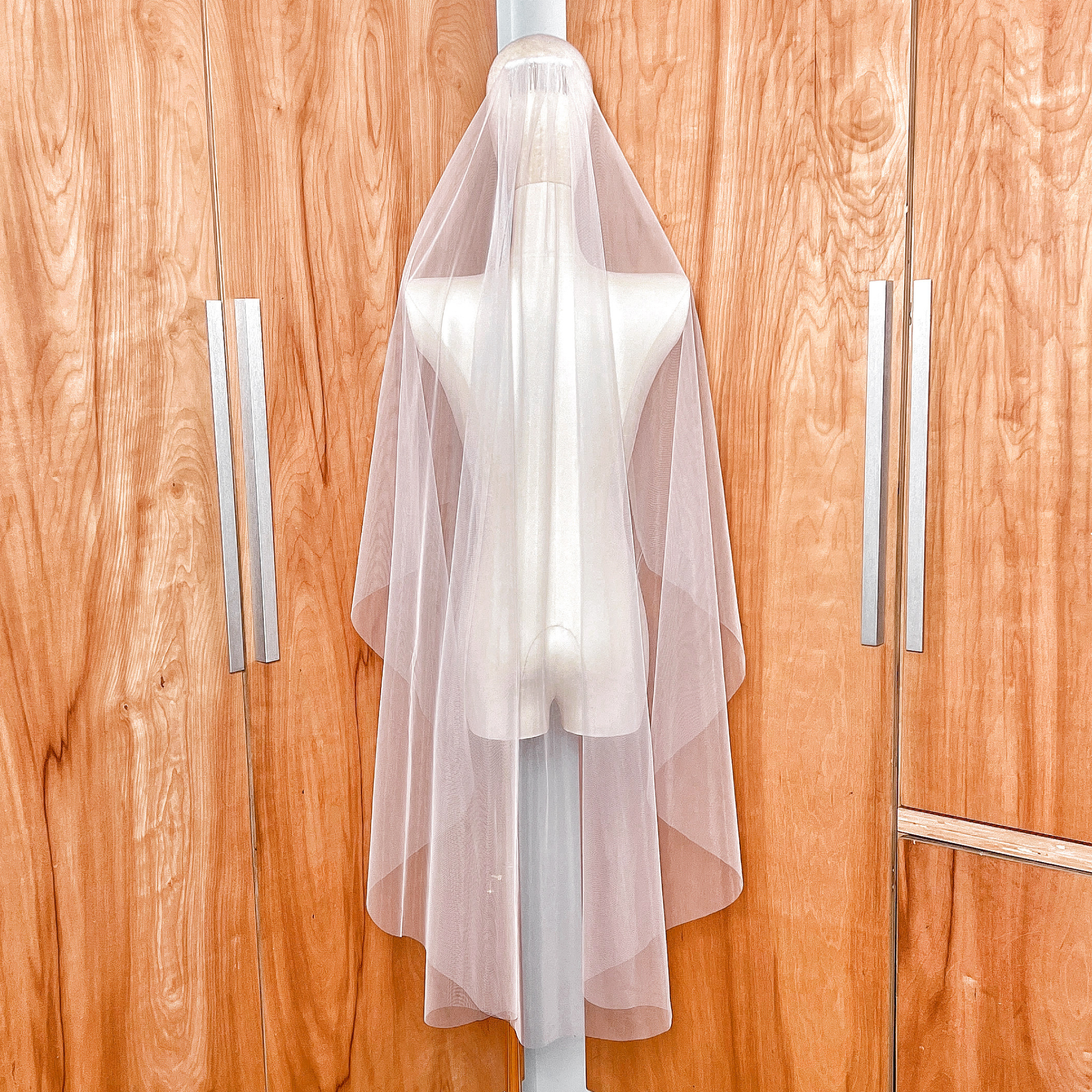 Back view of a knee-length wedding veil featuring a graceful cascade cut and minimalist raw edge.