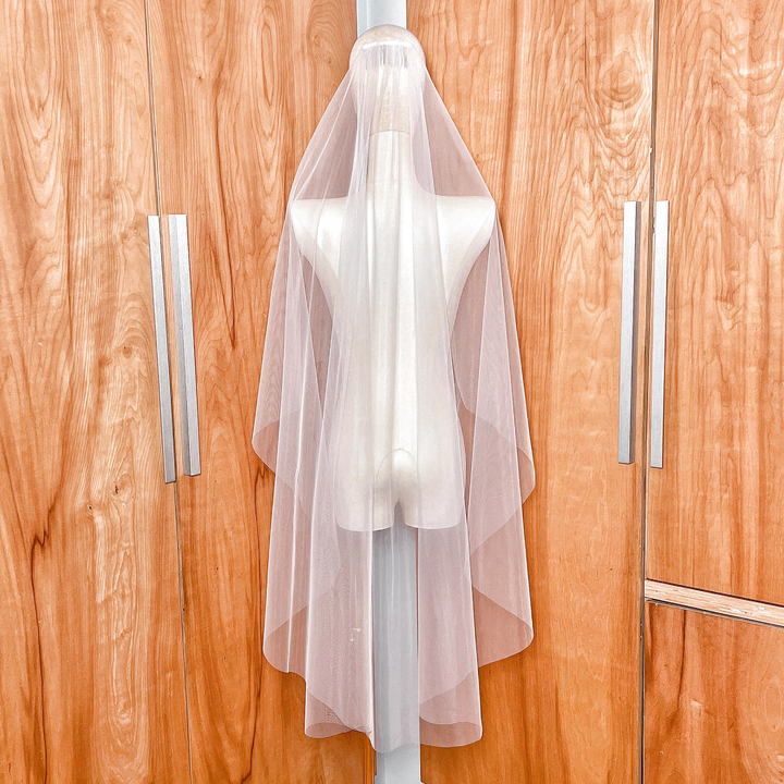 Back view of a knee-length wedding veil featuring a graceful cascade cut and minimalist raw edge.