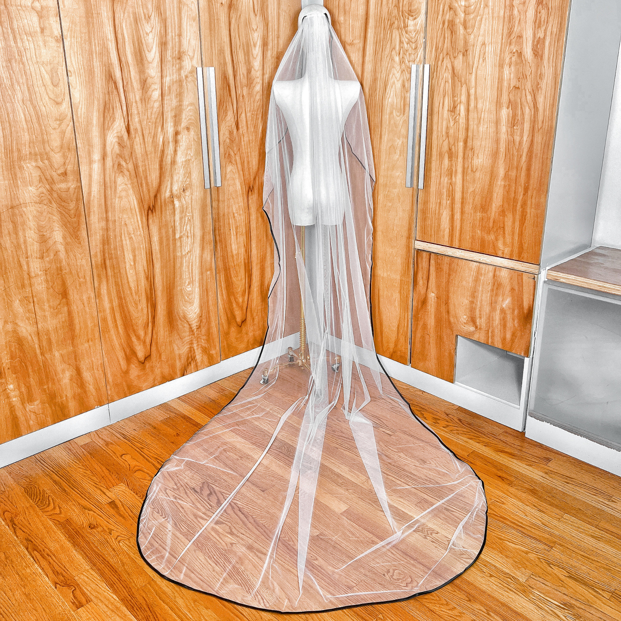 Rear view of a cascading cathedral length bridal veil featuring a bold black satin edge.