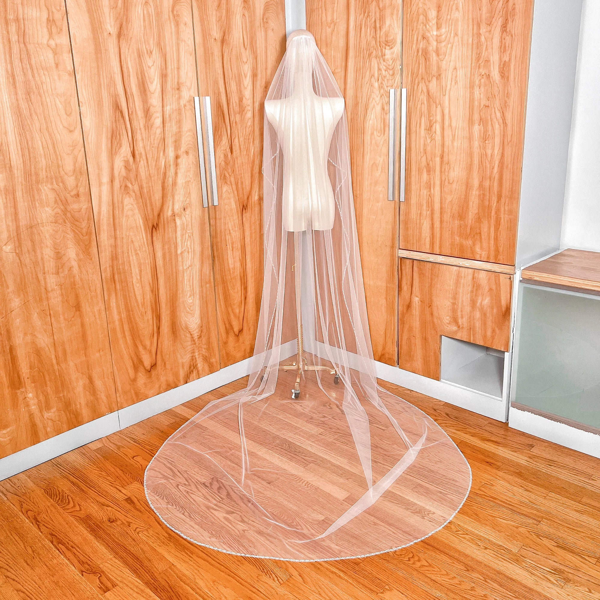 Back view of a cathedral length wedding veil featuring a delicate cascading beaded edge that catches the light.