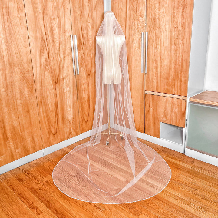 Back view of a cathedral length wedding veil featuring a delicate cascading beaded edge that catches the light.