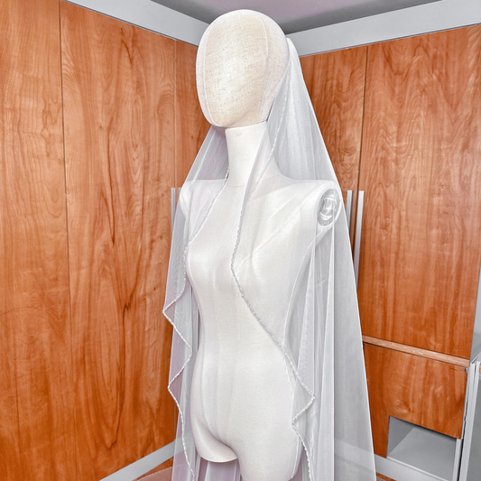 Side profile of a cathedral length wedding veil featuring a cascading beaded trim.