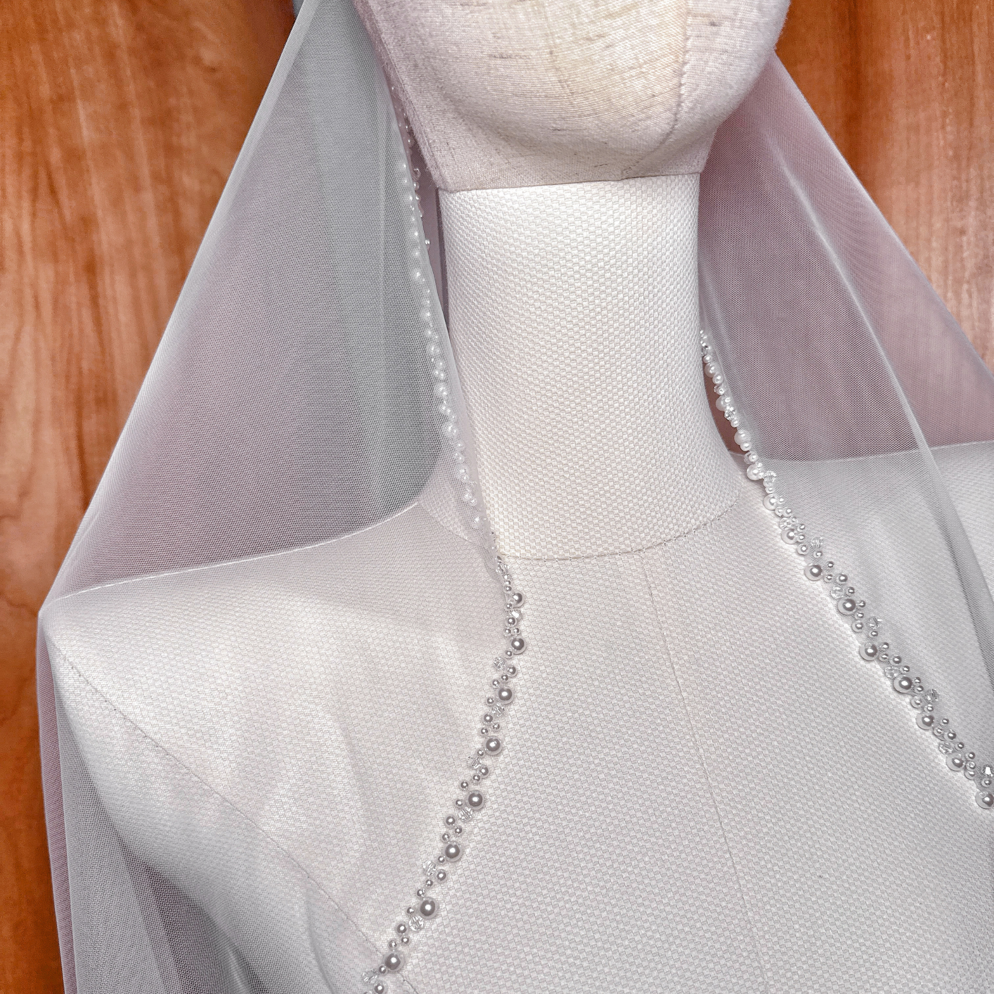 Detailed view of the cascading fingertip length pearl edge wedding veil.