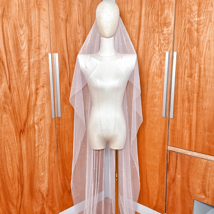 Front view of a cascading wedding veil with scattered white pearls of varying sizes.