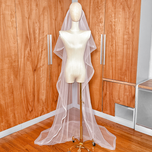 Cathedral length angel cut wedding veil with 1" horsehair trim shown on a mannequin for a dramatic, cascading bridal look.
