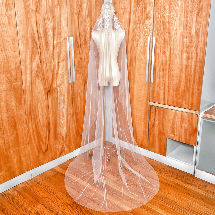 Full-length back view of a 118-inch beaded lace mantilla wedding veil showing the dramatic train trailing behind a mannequin.
