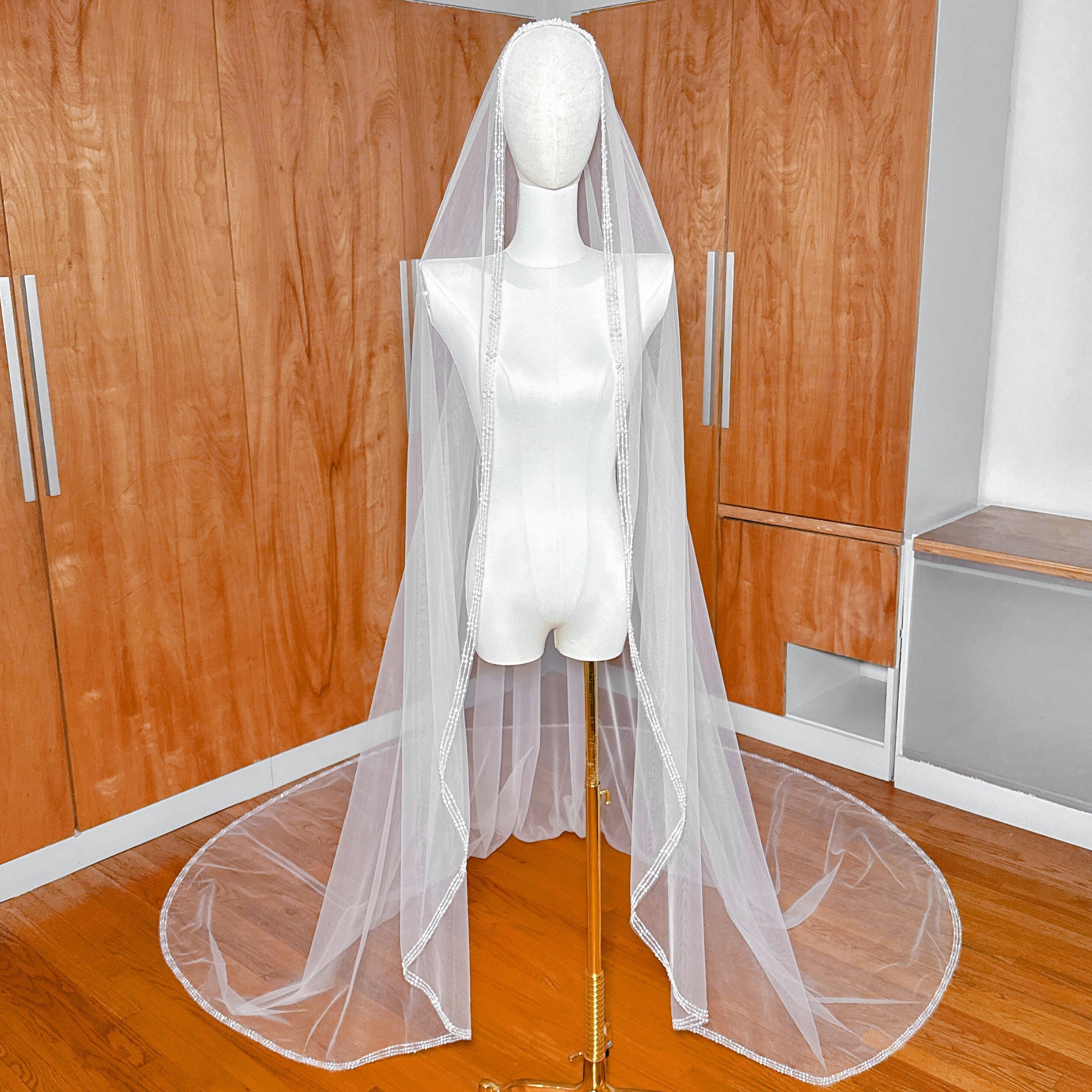 Cathedral length bridal veil with intricate pearl and crystal beading on a mannequin.