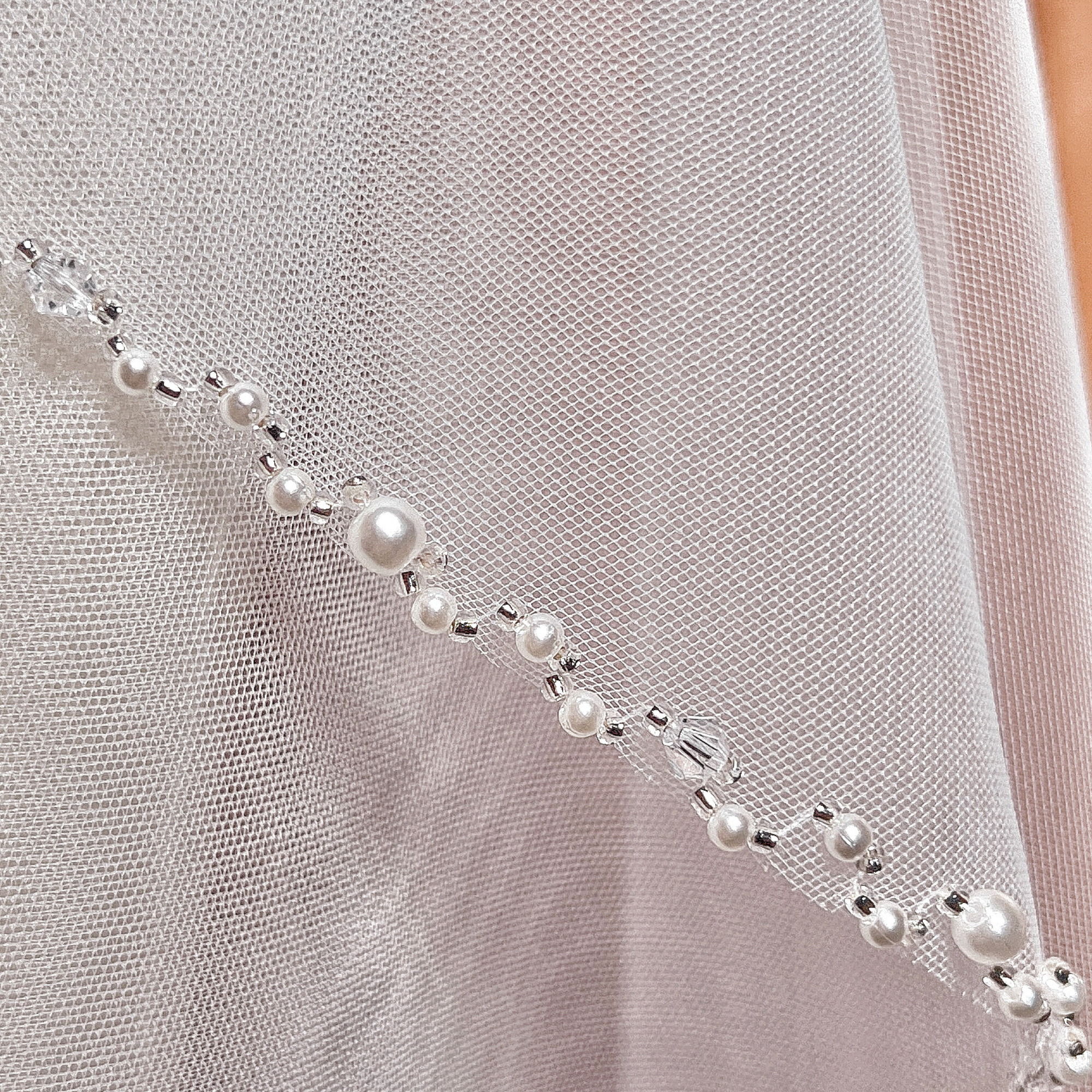 Close-up of the delicate pearl beaded edging on an angel cut cathedral wedding veil.
