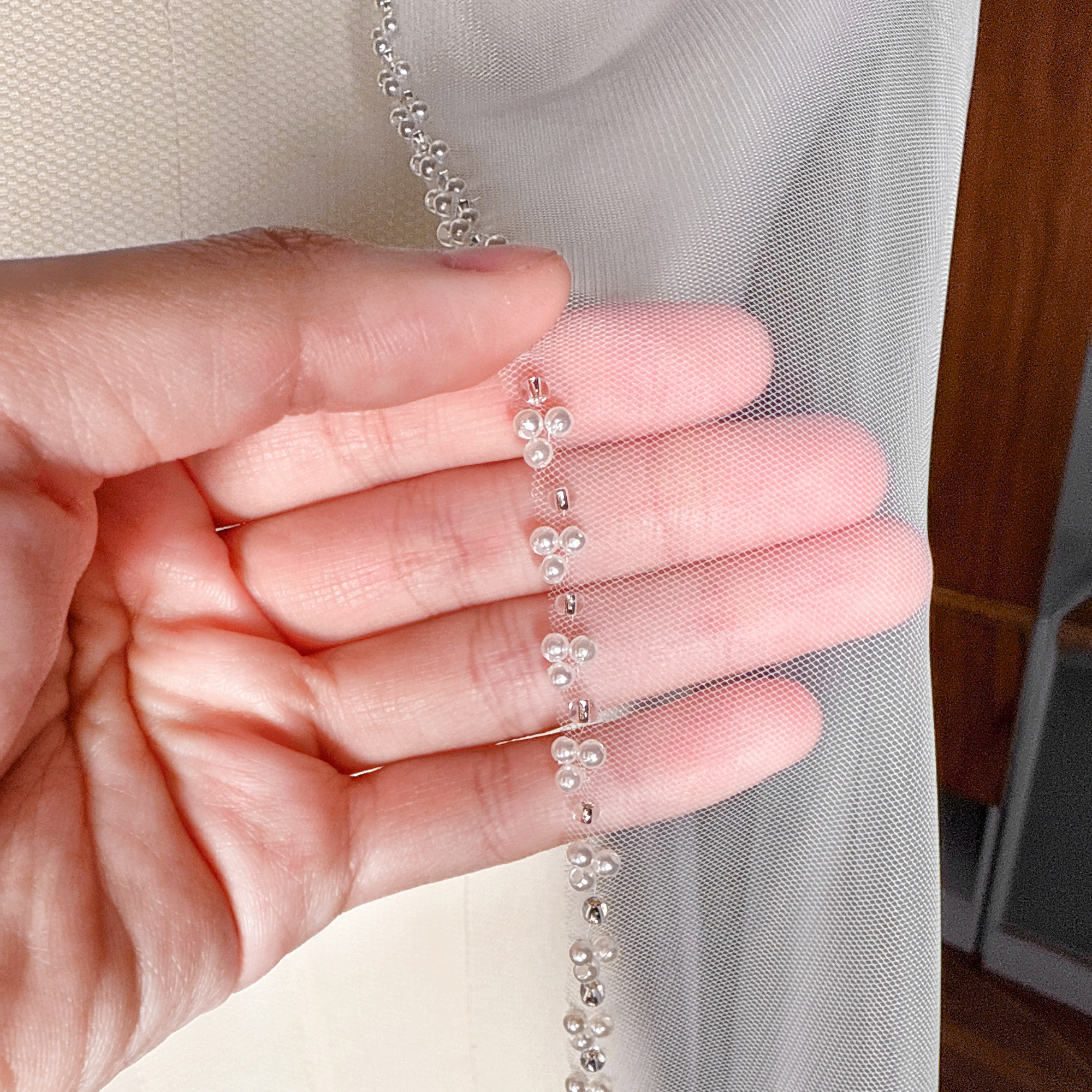 Detailed view of the intricate beaded trim on a cascade wedding veil in cathedral length.