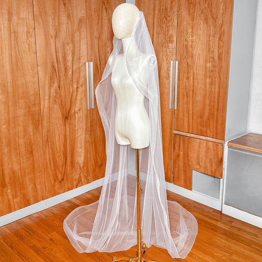 Side view of a cathedral cascade wedding veil on a mannequin highlighting the romantic waterfall drape and horsehair edging.