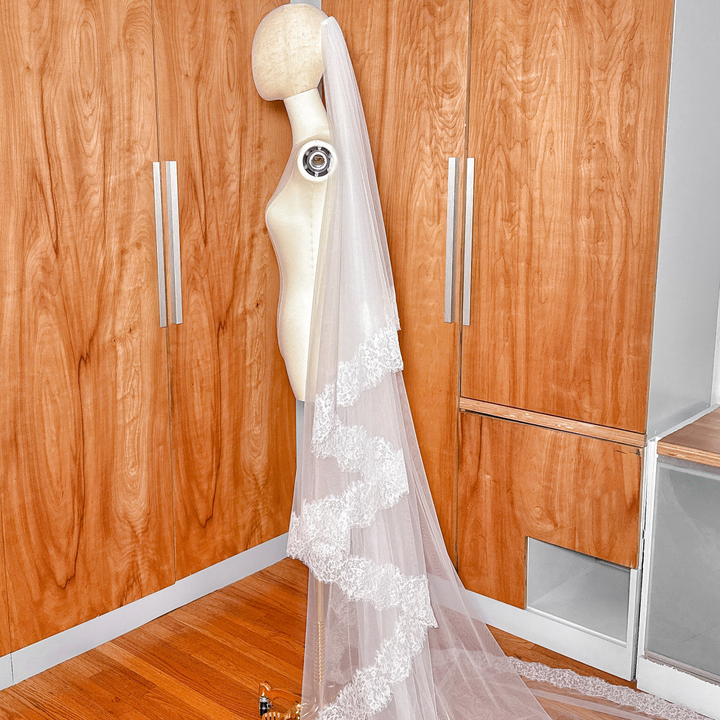 Long cathedral length bridal veil featuring intricate Chantilly lace edging on a mannequin.