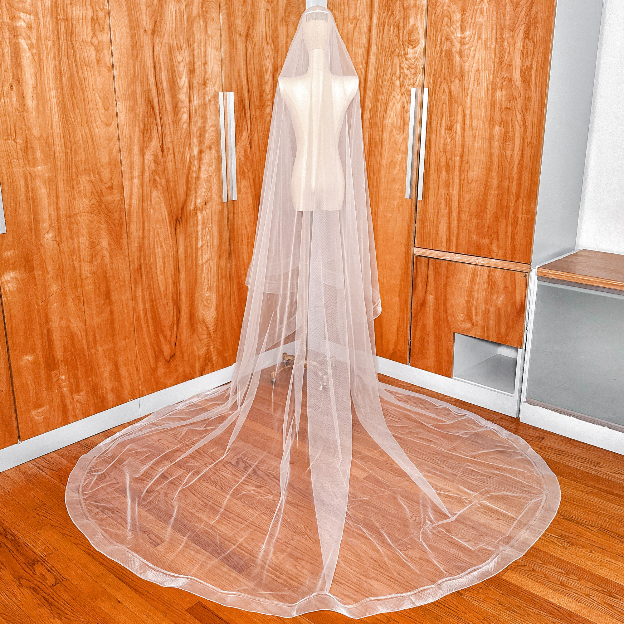 Rear view of a cathedral length double horsehair wedding veil draped on a dress form.