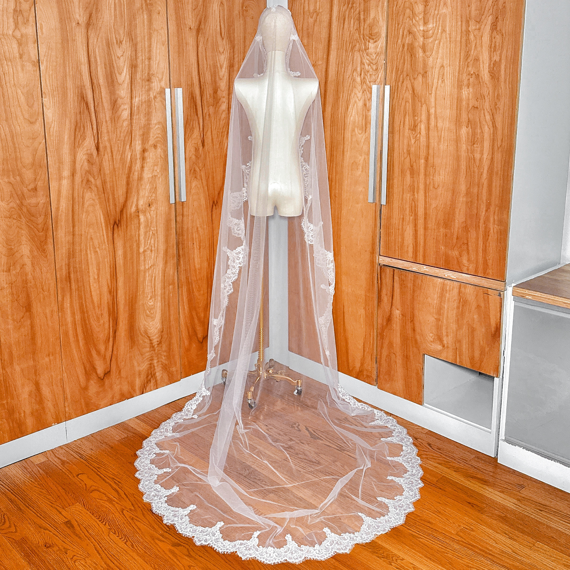 Full back view of the Alençon lace mantilla wedding veil in cathedral length displayed on a mannequin.