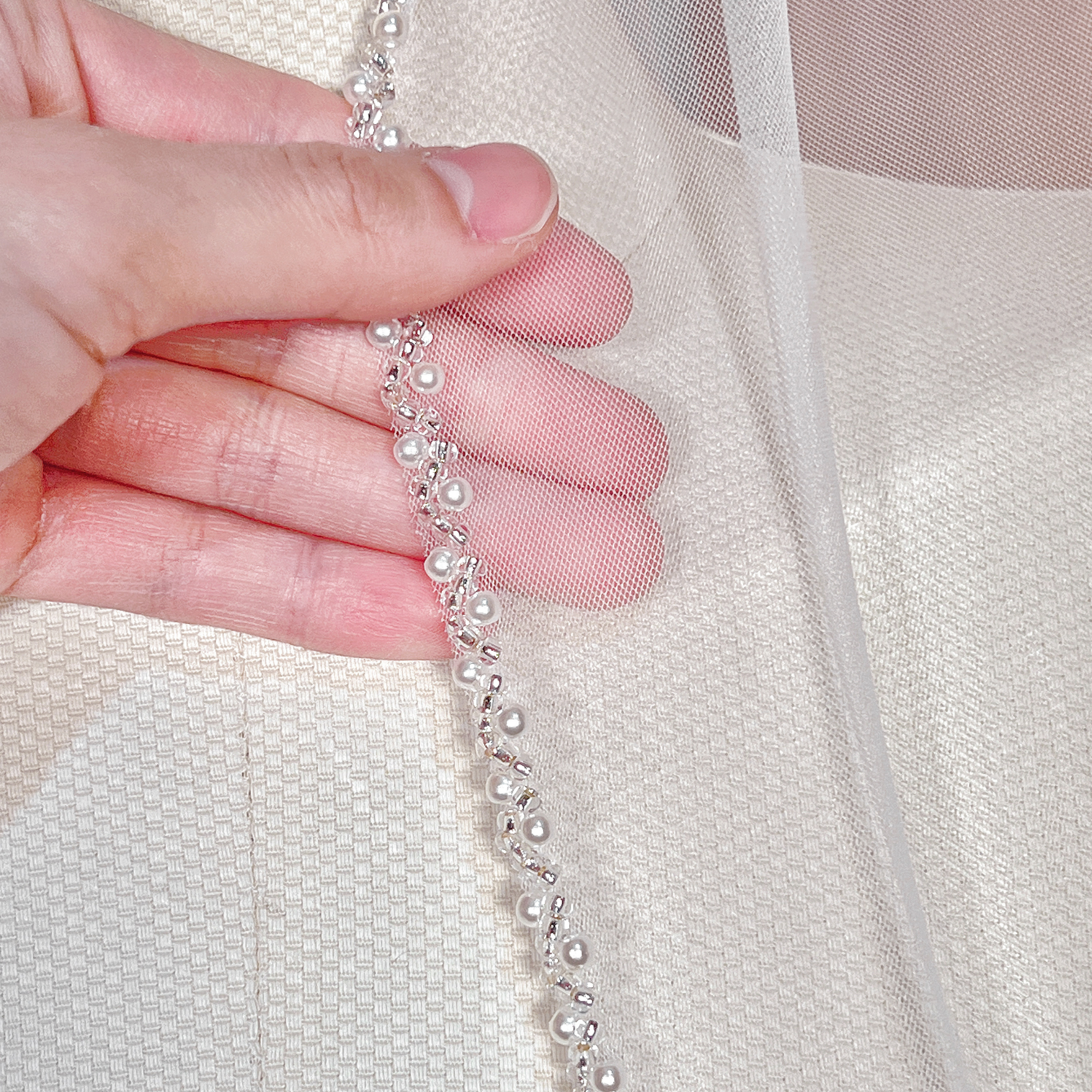 Close-up view of the intricate beaded edge on a soft tulle cathedral wedding veil.