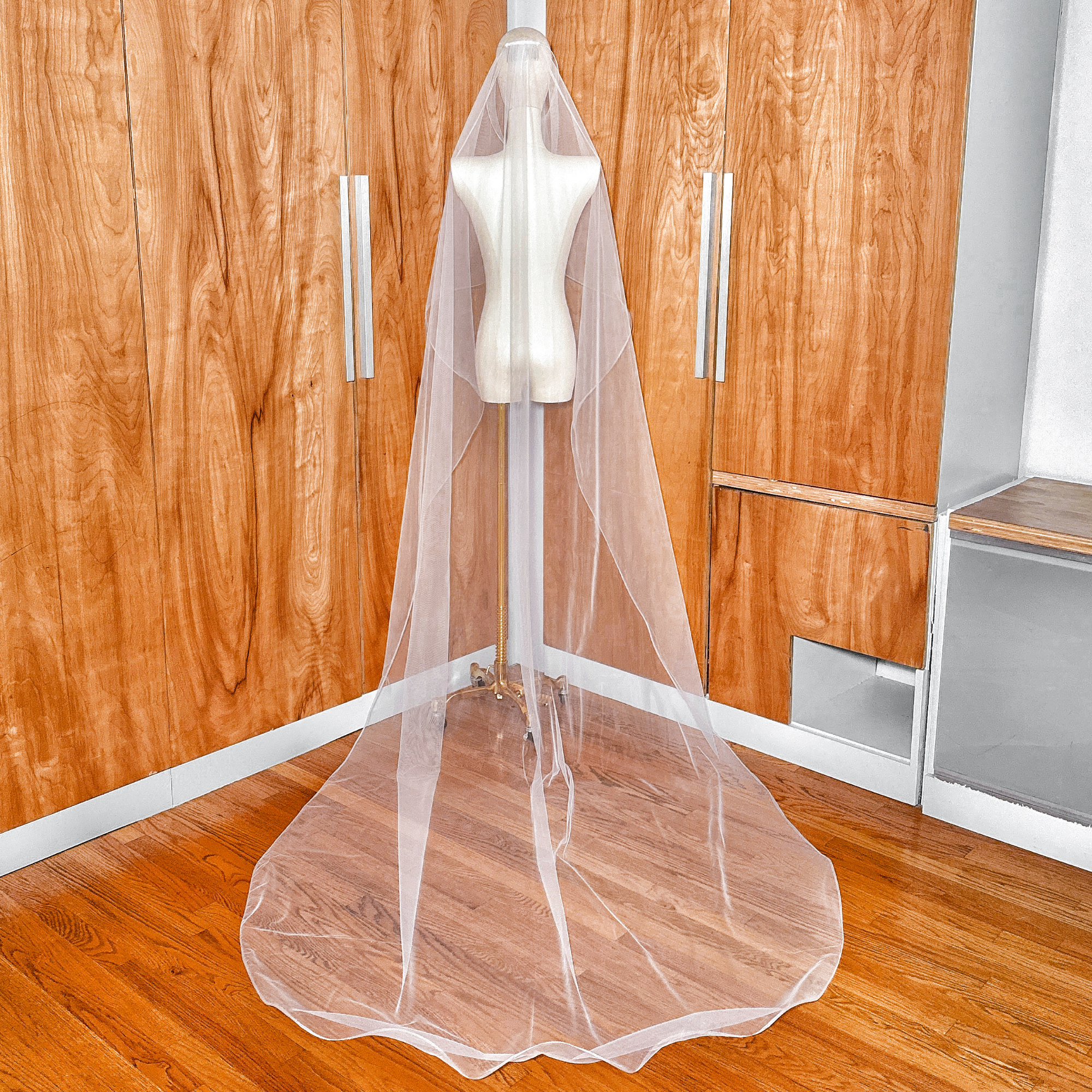 Back view of a cascading bridal veil in cathedral length featuring a delicate 1/8" horsehair edge on a dress form.