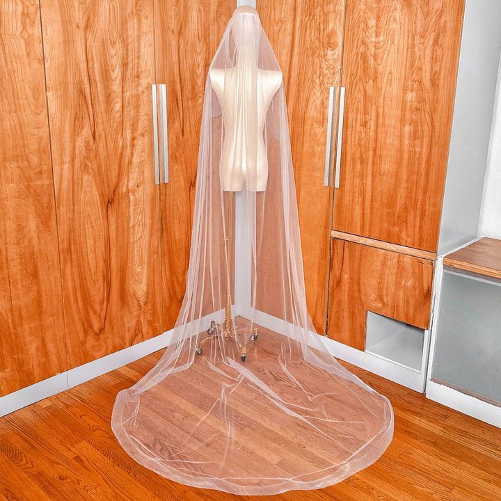 The long train of a cathedral-length cascade wedding veil with horsehair trim spread out behind a mannequin.