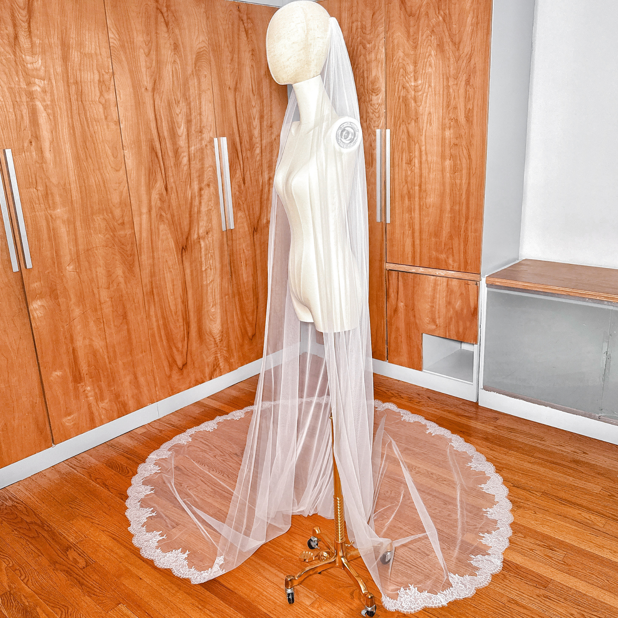 Full-length side profile of a cathedral Chantilly lace wedding veil on a mannequin.