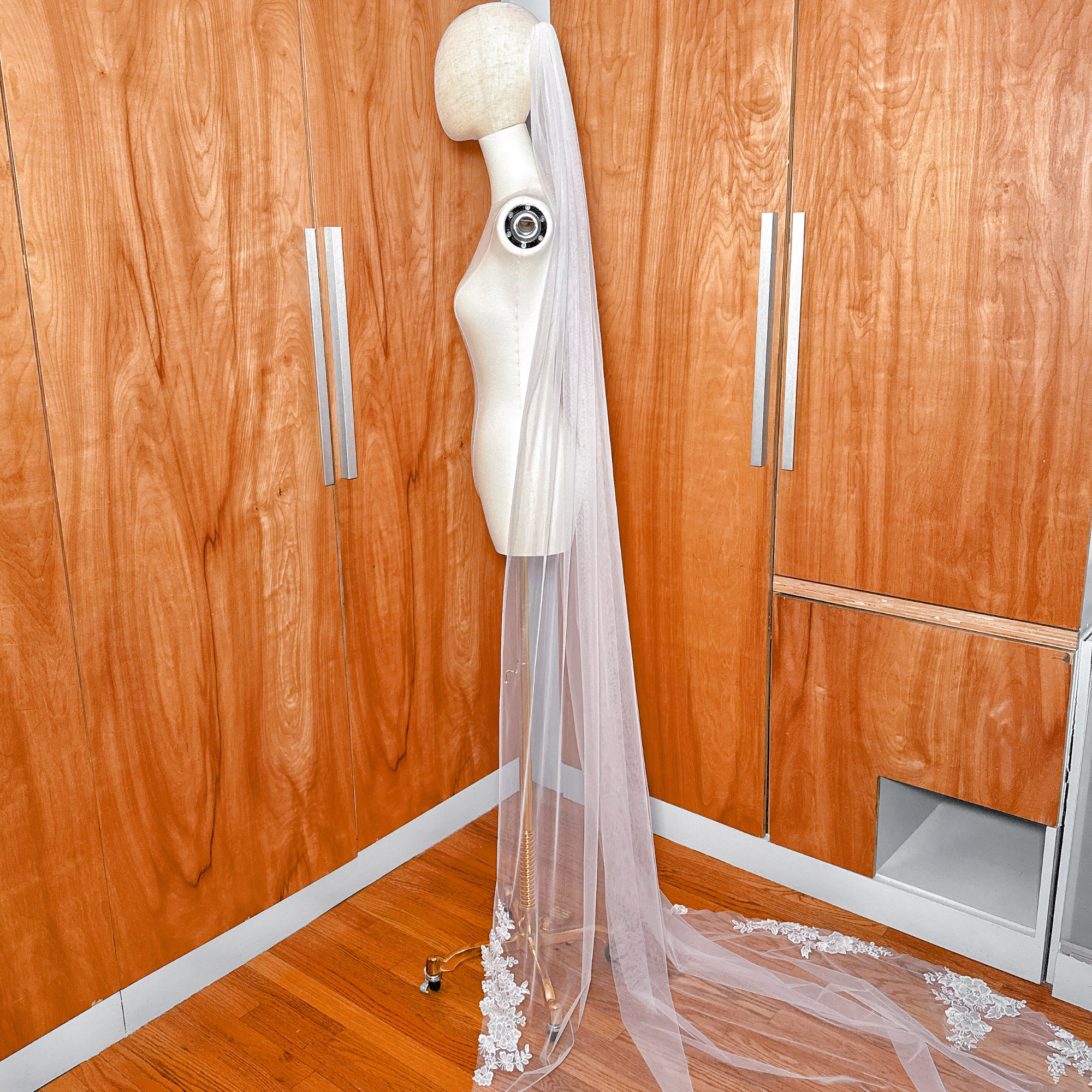 Sheer cathedral length bridal veil with delicate floral applique on a bridal mannequin.