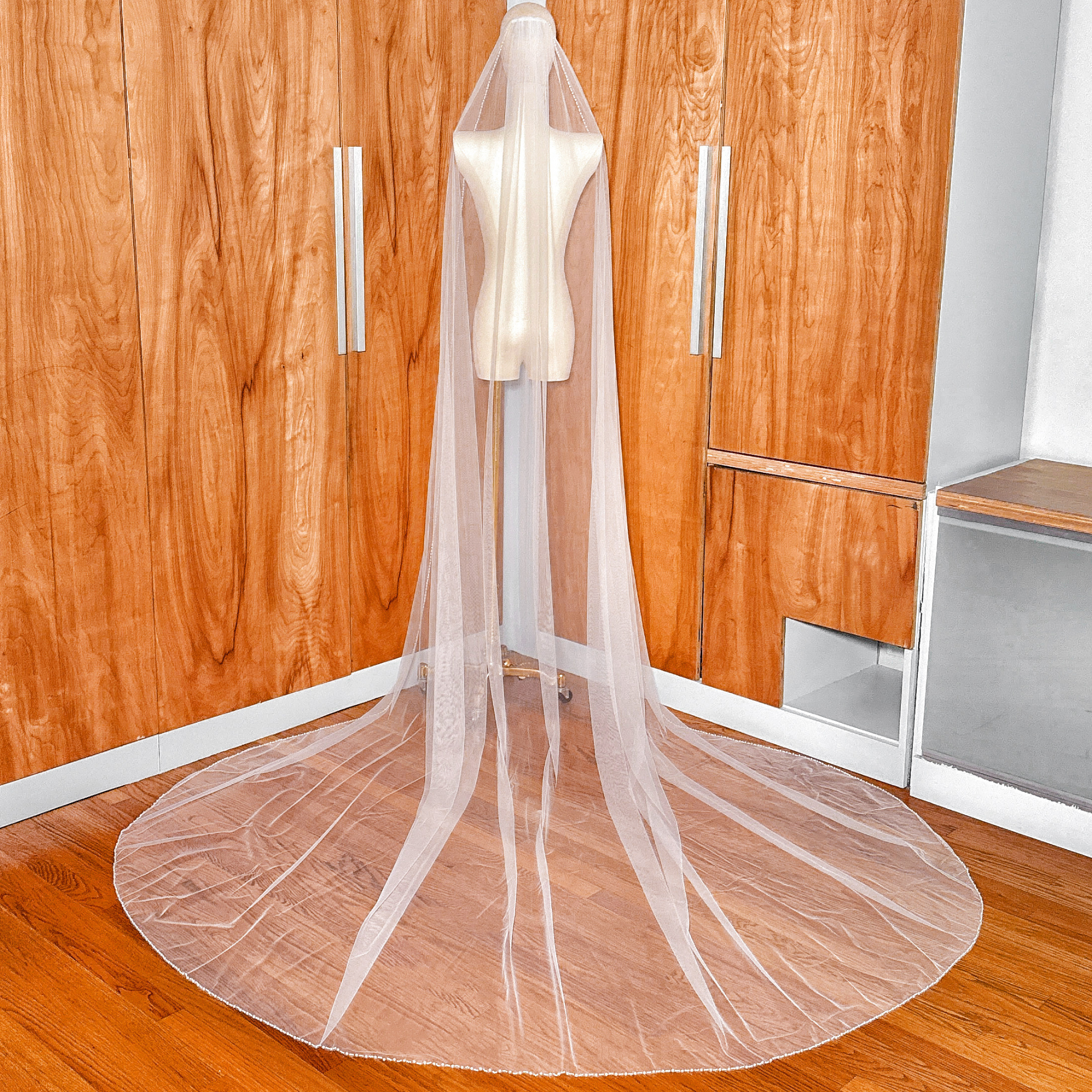 Back view of a cathedral length wedding veil with a pearl trim edge, showcasing its dramatic 118-inch trail.