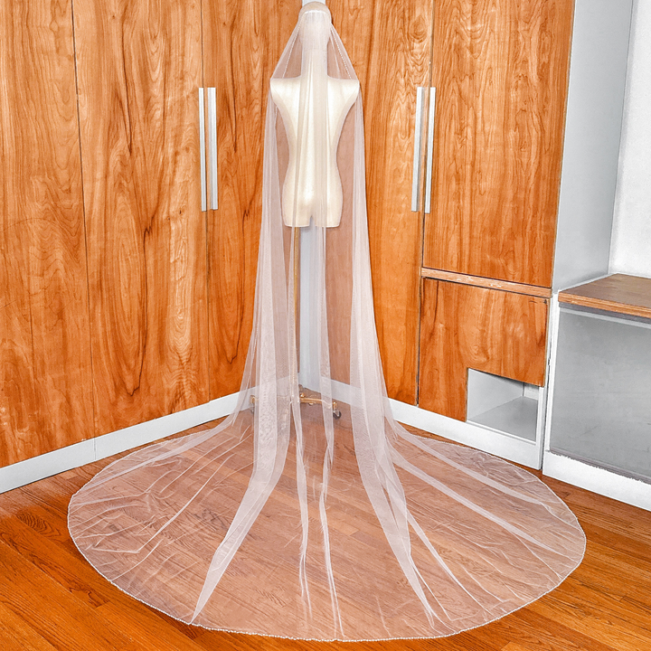 Back view of a cathedral length wedding veil with a pearl trim edge, showcasing its dramatic 118-inch trail.