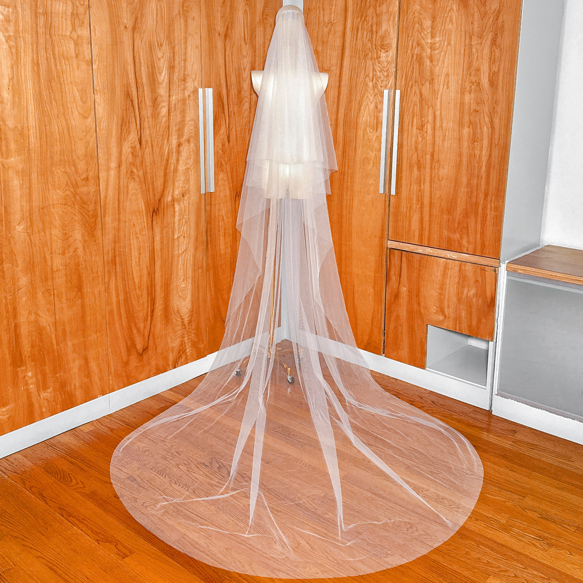 Full-length back view of a soft two-tier cathedral veil on a mannequin showing the long train.