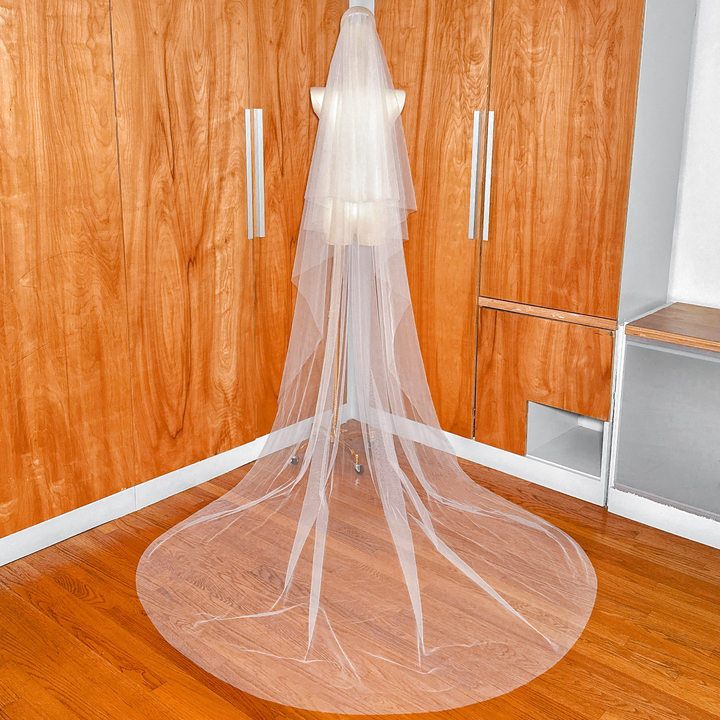 Full-length back view of a soft two-tier cathedral veil on a mannequin showing the long train.