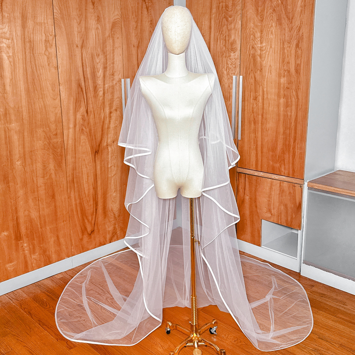 High-angle view showcasing the full drama and wide train of a two tier ribbon edge cathedral wedding veil with blusher.