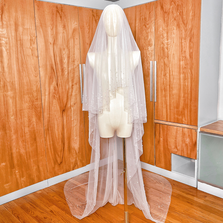 Full view of a cathedral length two tier scattered pearl wedding veil flowing from a mannequin.